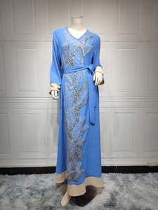 Détail d'une robe longue bleue avec broderie complexe de paillettes dorées et argentées