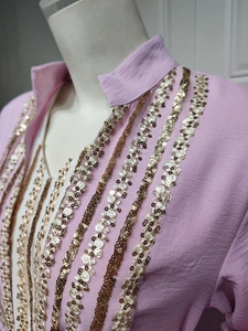 Detailed view of sequins embroidery on pink dress with bubble sleeve fabric texture