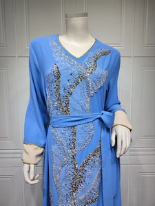 Détail d'un caftan bleu avec broderie de paillettes argentées et bordure dorée au col