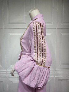 Detail of pink dress featuring puff sleeves with gold sequin vertical stripes