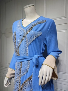 Détail de robe bleue à manches longues avec broderie papillon en paillettes et col en V