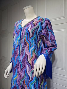 Detail of vibrant wavy print dress featuring long fringe sleeves and decorative blue buttons