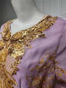 Close-up of golden embroidery and sequins on the purple tulle neck of a formal dress