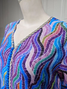 Detail of crystal V-neckline and braided tassel closure on colorful ethnic print dress