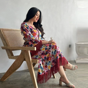 Ethnic bohemian long dress with vibrant floral prints and red fringe tassels on a model