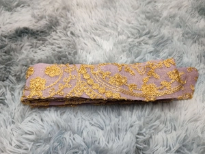 Detailed close-up of intricate lilac and gold floral embroidery on elegant fabric