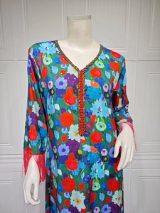 Detail of V-neckline with red-gold braided trim and abstract floral print on dress