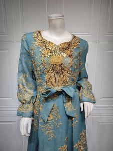 Detailed close-up of golden floral embroidery and sequin applique on grey-blue dress
