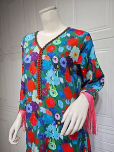 Detail of vibrant floral print dress featuring V-neckline and bright pink tassel cuffs