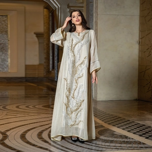 Elegant beige kaftan maxi dress with gold sequin embroidery in a luxury hallway
