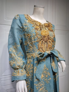 Detail of intricate gold floral embroidery and sequins on teal kaftan dress sleeve