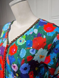 Close-up of ethnic V-neck dress with gold floral print and red braided knot buttons