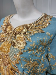 Detailed embroidery with gold sequins and textured patterns on a turquoise party gown