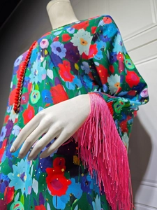 Detail of ethnic floral dress with red pom-pom trim and pink fringe tassels on the sleeve
