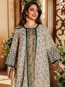Detail of elegant beige dress featuring intricate green embroidery and golden sequins