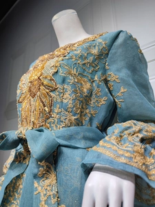 Macro view of detailed gold embroidery and sequins on deep blue ethnic party dress
