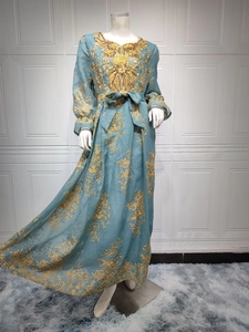 Detailed close-up of intricate gold embroidery and heavy beadwork on the teal dress