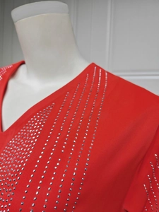 Gros plan de strass argentés brillants sur le col en V d'une robe de soirée en mousseline rouge