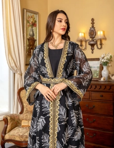 Detail of elegant black mesh abaya featuring white leaf prints and gold sequin embroidery