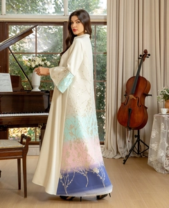 Detailed close-up of golden embroidery and gradient hem on elegant white abaya dress
