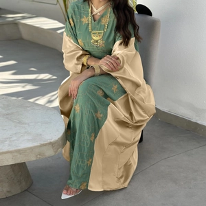 Detail of dark green satin dress with gold embroidery and champagne kaftan overlay