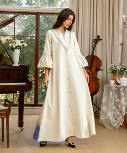 Close-up of elegant embroidery on a cream satin long dress with flared sleeves