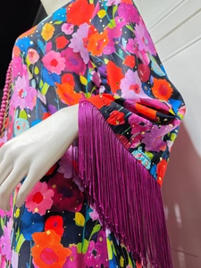 Detail of bohemian floral print dress featuring gold foil accents and purple tassel sleeves