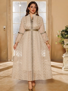 Close-up of elegant golden leaf embroidery and black-gold trim on champagne gown sleeves