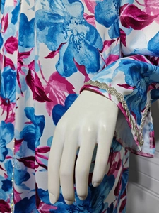 Detailed macro shot of blue floral print and rhinestone trim on white satin dress