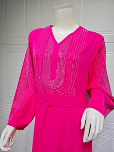Détail de strass sur une robe de soirée en mousseline fuchsia à manches longues