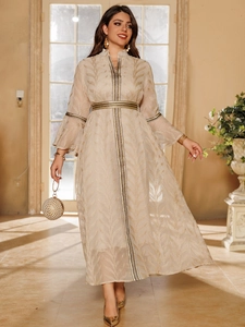 Detailed embroidery of gold leaf patterns on a champagne kaftan dress with beaded clutch