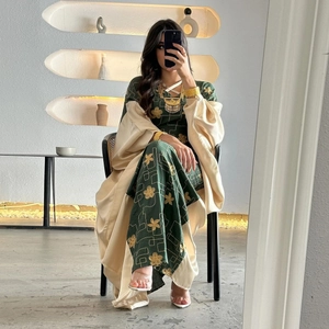 Detail of green dress with gold floral embroidery and beige satin outer abaya