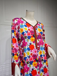 Detail of bohemian long sleeve dress showing floral patterns and red tassels on cuffs