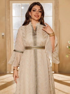 Detail of elegant beige maxi dress with gold leaf patterns and ornate braided trim accents