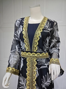 Detail of gold sequin embroidery and white leaf stitching on a black mesh Abaya
