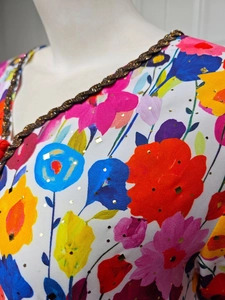 Detail of V-neckline with woven trim and gold foil floral print on ethnic maxi dress