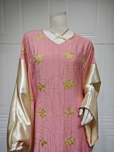 Detail of pink embroidered abaya with golden satin sleeves and floral sequin patterns