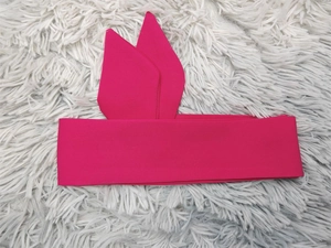 Détail du bandeau rose fuchsia en tissu avec oreilles de lapin sur tapis en peluche blanc