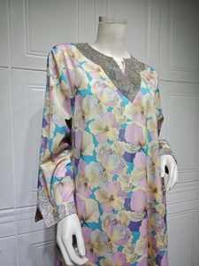 Détail d'une robe longue fleurie avec paillettes argentées au col et poignets