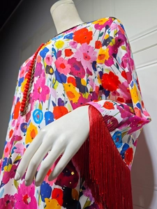 Detailed view of women's dress featuring floral prints and red fringe tassels on cuffs