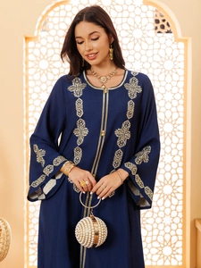 Détails de broderie géométrique dorée sur la manche et l'encolure du caftan bleu marine