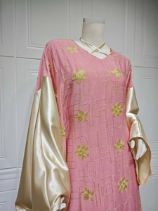 Detail showing pink dress with golden floral embroidery and flared satin sleeves