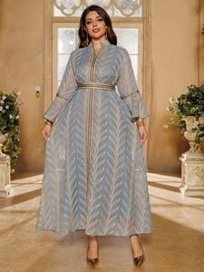 Close-up of golden feather embroidery and ruffled cuff on elegant light blue dress