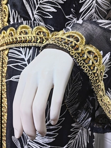 Detail of black chiffon kaftan featuring gold lace embroidery and white leaf patterns