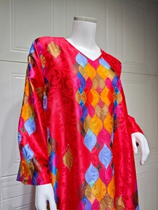 Detail of red satin kaftan featuring intricate diamond patterns and rhinestone accents