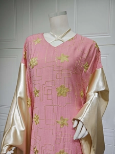 Close-up of pink embroidered dress with gold floral patterns and satin sleeves