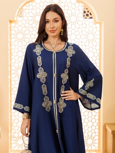 Détails de broderies géométriques dorées et boutons sur une robe kaftan bleu marine