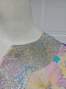 Détail de l'encolure avec strass étincelants et imprimé floral aux couleurs vives