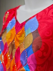 Macro shot of V-neck red jacquard dress with colorful print and rhinestone beadwork