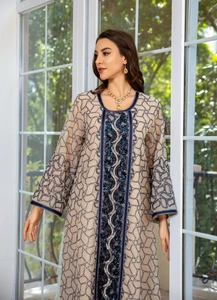 Detail of blue sequin embroidery and intricate patterns on beige mesh dress